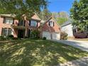 Traditional brick home with a manicured lawn, lush trees, and a two-car garage at 713 Parkside Dr, Woodstock, GA 30188