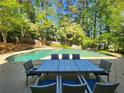 Inviting outdoor pool surrounded by mature trees and a patio area with outdoor seating at 7635 Blandford Pl, Atlanta, GA 30350