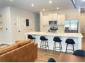 Open-concept living and dining area with a modern kitchen featuring a large island, stainless appliances, and stylish bar stools at 251 Turner Ln, Woodstock, GA 30188