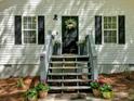 Up close exterior view of the front door, black shutters, plants, and wooden stairs at 113 Fowler Dr, Bowdon, GA 30108