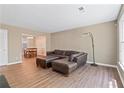 Open-concept living room features hardwood floors and a comfortable leather sofa with ottoman at 223 Chads Ford Way, Roswell, GA 30076