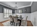 A dining room with gray walls, white wainscoting, hardwood floors, and modern lighting at 3330 Camellia Ln, Suwanee, GA 30024