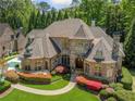 Elegant home with stone facade, lush landscaping, and a multi-sport court adjacent to the driveway at 841 Camden Park Ne Ct, Atlanta, GA 30342