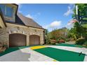 Three-car garage and sport court are highlighted against mature trees in this property view at 841 Camden Park Ne Ct, Atlanta, GA 30342