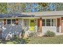 Close up on the light grey brick facade and the vibrant lime green front door with wooden shutters on the windows at 2376 Falls River Dr, Lithia Springs, GA 30122