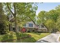 A beautiful Tudor-style home with lush landscaping and mature trees in the front yard at 305 Spindle Ct, Sandy Springs, GA 30350
