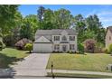 Beautiful two-story home featuring manicured lawn, mature trees, and a classic, inviting facade at 4680 Glen Level Dr, Sugar Hill, GA 30518