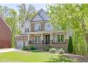 Inviting two-story home with stone accents, a covered front porch, and mature trees surrounding the property at 7035 W Mountain Xing, Cumming, GA 30041