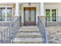 Close-up of the home's entrance, featuring a decorative front door, stone pillars, and wrought iron railings at 7035 W Mountain Xing, Cumming, GA 30041