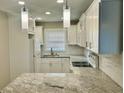 Well-lit kitchen featuring white cabinets, granite countertops, a modern faucet, and sleek pendant lighting at 2961 Stone Mountain St, Lithonia, GA 30058