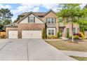 Two-story brick home featuring a three car garage and a beautifully landscaped front yard at 1304 Slate Bend Dr, Dacula, GA 30019