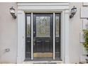 Close up of decorative front door with sidelights and a brass kick plate, flanked by sconces at 861 Southland Pass, Stone Mountain, GA 30087