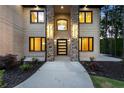 A well-lit front entrance featuring stone columns and a modern black front door with glass panels at 1540 Brooks S Rd, Lawrenceville, GA 30045