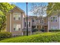 View of two-story condo with tan siding, black shutters, and manicured green landscaping at 2400 Cumberland Se Pkwy # 803, Atlanta, GA 30339