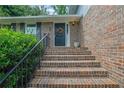 Brick stairs with black railing lead to front door, adorned with wreath, flanked by green bushes at 5618 Fern Creek Sw Dr, Lilburn, GA 30047