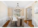 Elegant dining room with stylish chandelier, wainscoting, and wood floors at 720 Lakeglen Dr, Suwanee, GA 30024