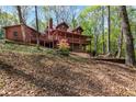 Spacious back porch and deck of a log home in a wooded backyard provides ample room for outdoor seating at 6515 Namon Wallace Dr, Cumming, GA 30028
