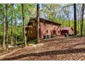 Back exterior view of a rustic log home surrounded by lush greenery and mature trees at 6515 Namon Wallace Dr, Cumming, GA 30028