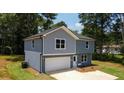 This two-story home features mixed siding, an attached garage, and a front lawn with mature trees surrounding the property at 1351 E Atlanta E Rd, Stockbridge, GA 30281