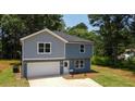 Two-story home boasts a gray-blue exterior, attached garage, and a well-manicured lawn surrounded by mature trees at 1351 E Atlanta E Rd, Stockbridge, GA 30281
