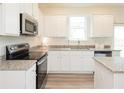 Modern kitchen featuring white cabinets, stainless steel appliances, granite countertops, and wood-look flooring at 2680 Ne Almand Ne Ln, Conyers, GA 30013