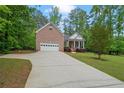 Lovely brick home with an attached garage, front porch, and long driveway at 5071 Woodmont Dr, Villa Rica, GA 30180