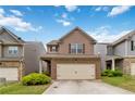 Inviting two-story home featuring a brick and neutral toned facade, a two-car garage, and well-manicured landscaping at 5885 San Gabriel Ln, Atlanta, GA 30349