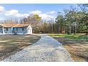 Long gravel driveway leading to a charming home with a spacious front yard and mature trees at 900 Stone Lea Trce, Oxford, GA 30054
