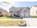 Inviting two-story brick home with a well-kept lawn, colorful flowers, and an attached two-car garage at 3448 Clear Stream Ne Run, Auburn, GA 30011