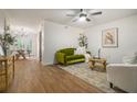 Bright living room featuring hardwood floors, plush green sofa, and ample natural light at 2294 Salt Springs Pl, Austell, GA 30168