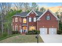 Charming red brick home featuring a two-car garage and manicured front yard, at dusk at 455 Cooper Woods Se Ct, Smyrna, GA 30082