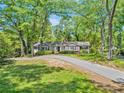 A picturesque home nestled among mature trees, boasting a long driveway and lush green lawn at 3150 Rilman Nw Rd, Atlanta, GA 30327