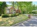 Brick home with lush landscaping and mature trees, complemented by a long driveway and manicured lawn at 120 Stanmore Ct, Roswell, GA 30075