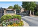 Arbor Chase community entrance with stone signage, colorful flowerbeds, and a security gate for privacy at 3065 Arbor Song Ct, Cumming, GA 30041