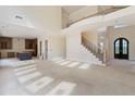 Expansive living room featuring a soaring ceiling, staircase, and an arched front doorway at 5694 Brendlynn Dr, Suwanee, GA 30024