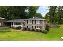 Two-story brick home with front porch, black shutters, and mature trees at 3925 Chicamauga Ne Dr, Kennesaw, GA 30144