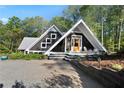 A-frame home with unique architectural details and a gravel driveway, surrounded by lush greenery at 6255 Lakeview Dr, Buford, GA 30518