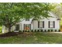 Charming white brick home with lush front yard landscaping, dark shutters and a covered front porch at 648 Gold Valley Pass, Canton, GA 30114