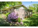 Brick house with mature trees and a lush landscaped yard with stone steps leading to the backyard at 3224 Laura Way, Winston, GA 30187
