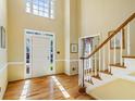 Sunlit foyer features hardwood floors and staircase and transom window above the front door at 815 Kings Arms Way, Alpharetta, GA 30022