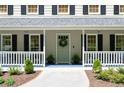 Charming front porch with seating area, plants, and traditional architectural details at 6005 Cherecobb Ln, Woodstock, GA 30188