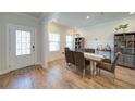 An open and inviting dining area with wood floors, a dining table, and a decorative entry door at 3690 Summerpoint Xing, Cumming, GA 30028