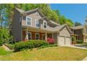 View of a two-story home with neutral siding, a brick porch, and an attached two-car garage at 127 Stoney Creek Pkwy, Woodstock, GA 30188