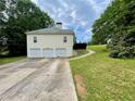 Rear exterior view showcasing the three-car garage and a well-maintained lawn and landscape at 25 Derby Dr, Hiram, GA 30141
