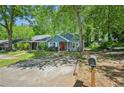 Inviting blue home boasts mature trees, a red front door, and a welcoming driveway at 5126 Farm Place Ne Dr, Woodstock, GA 30188