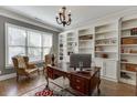 Charming home office with a large window, chandelier, hardwood floors, built-in bookshelves, and a desk at 6050 Eagle Close Ln, Sugar Hill, GA 30518