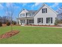 Elegant two-story house boasts a lush green lawn and striking white exterior with black shutters at 6680 Benchwood Path, Cumming, GA 30028