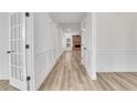 Hallway featuring wood floors, white trim and moulding and a stone fireplace in the living room at 6680 Benchwood Path, Cumming, GA 30028