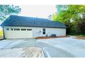 Expansive concrete driveway leads to a two-car garage, set against a backdrop of mature trees at 7675 Lanier View Rdg, Cumming, GA 30041