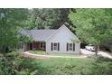 Landscaped front yard of single-story home with light blue siding, dark shutters, and a long driveway at 7675 Lanier View Rdg, Cumming, GA 30041
